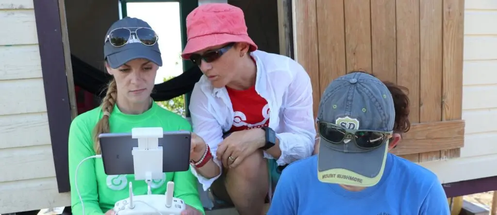 Three people discussing drone operation outdoors