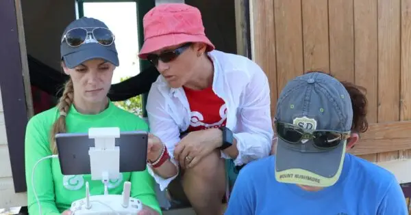 Three people discussing drone operation outdoors