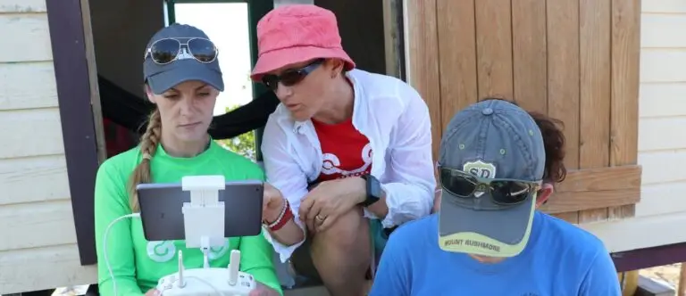 Three people discussing drone operation outdoors