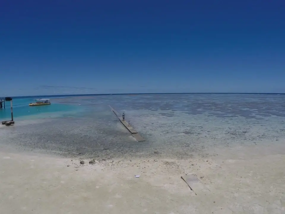 Vibrant blue waters and sandy shoreline at low tide.