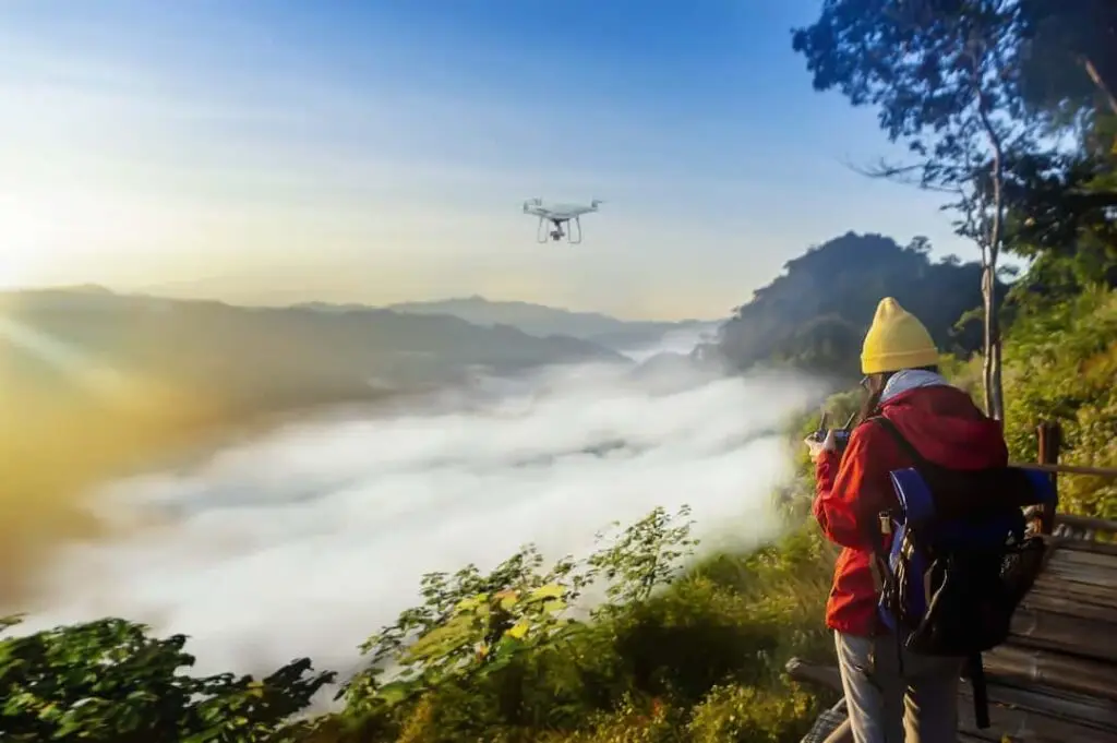 Person operating drone above misty mountainous landscape.