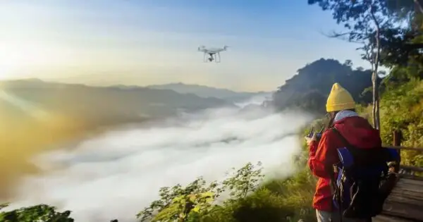 Person operating drone above misty mountainous landscape.