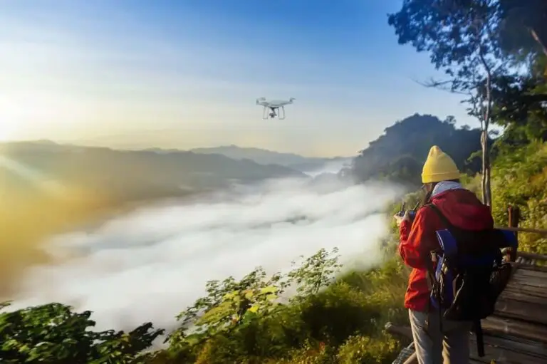 Person operating drone above misty mountainous landscape.