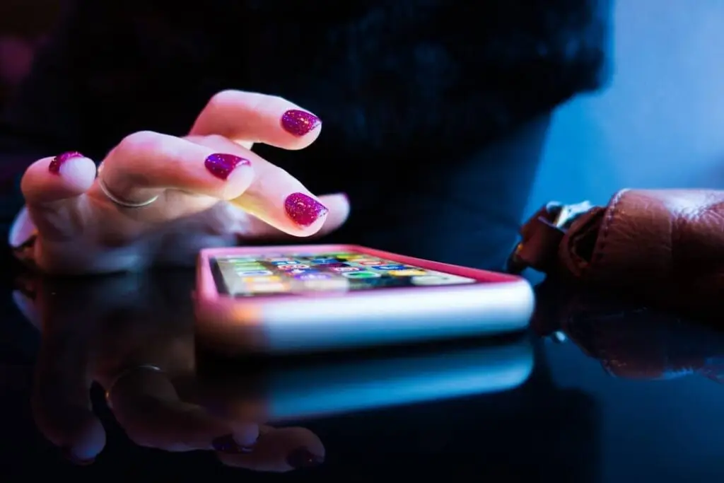 Person using a smartphone with bright nails.