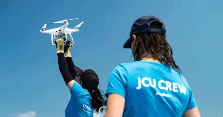 Person flying a drone under clear blue sky.