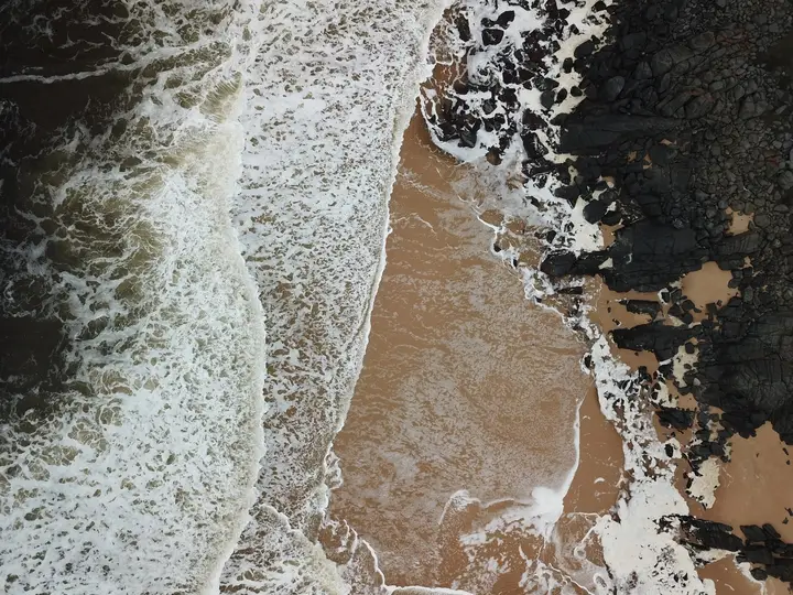 Aerial view of waves crashing on rocky coastline.