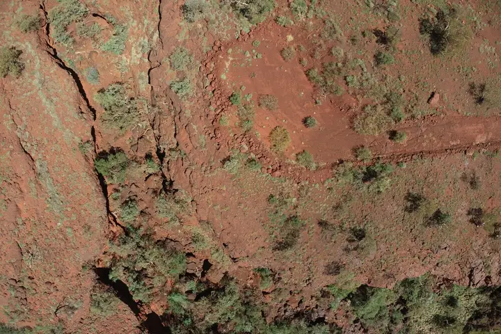Aerial view of red earth with sparse vegetation.