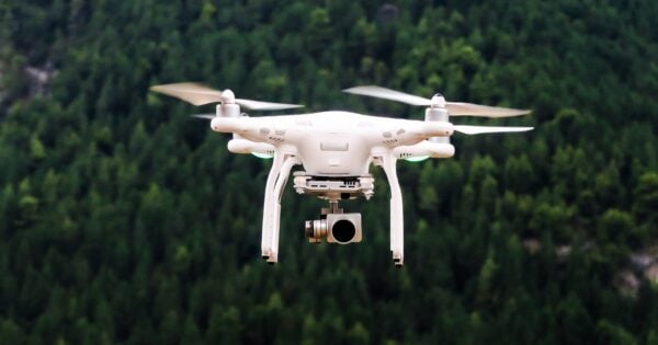 Drone flying over lush green forested landscape.