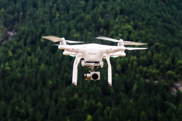 Drone flying over lush green forested landscape.