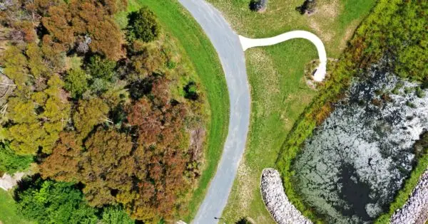 Aerial view of parkland with paths and pond.