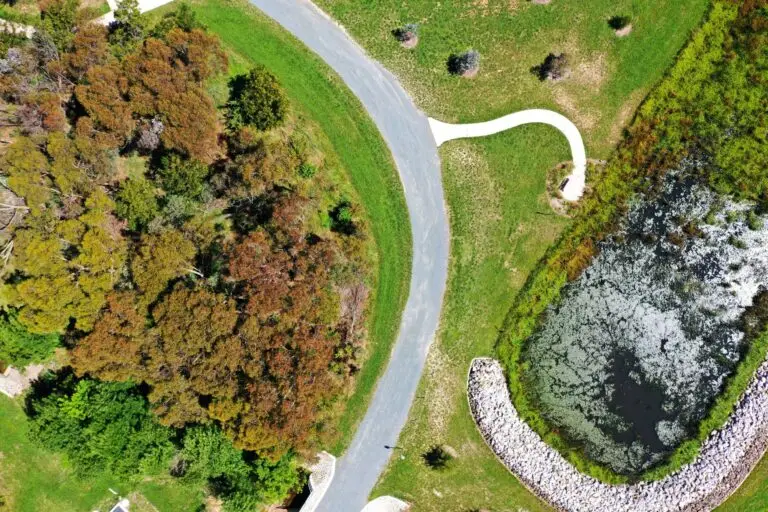 Aerial view of parkland with paths and pond.
