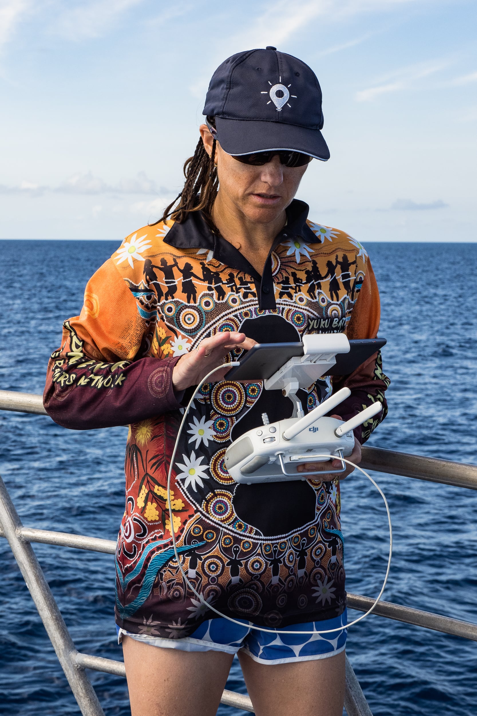 Woman on a boat with a remote controller and ipad with the ocean in the background
