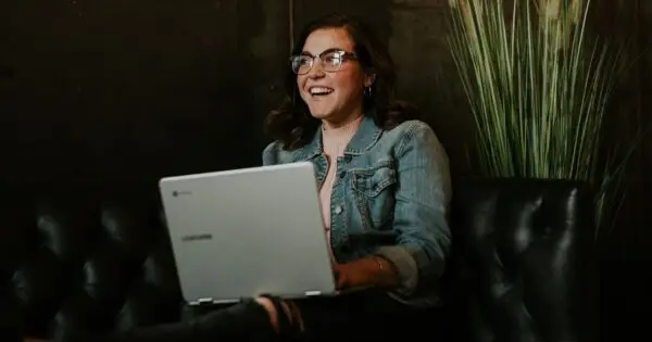Smiling woman using a laptop on a couch.