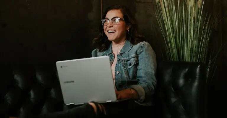 Smiling woman using a laptop on a couch.