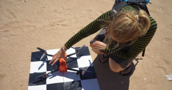Person inspecting a drone on sand