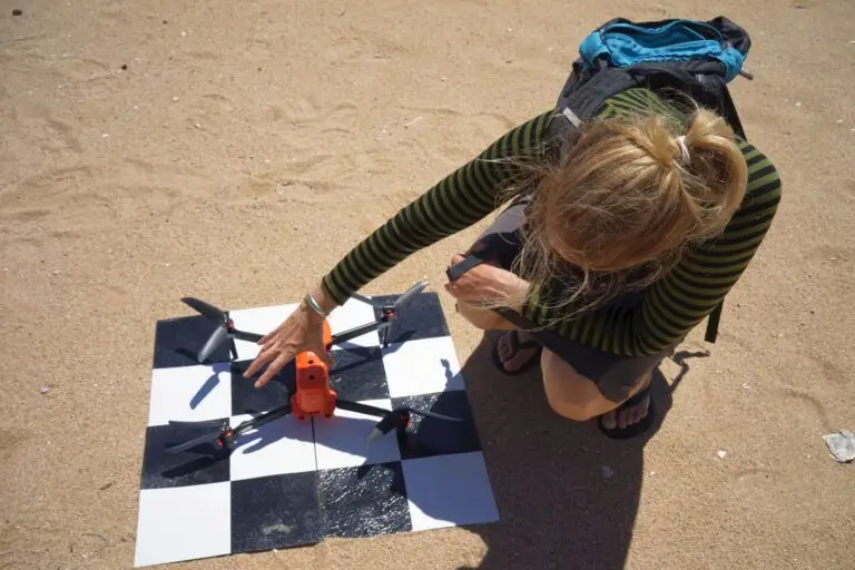 Person inspecting a drone on sand