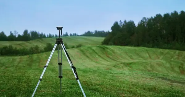 Tripod on green grass landscape with hills.