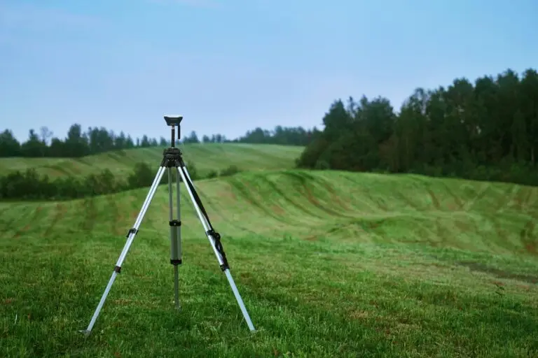 Tripod on green grass landscape with hills.