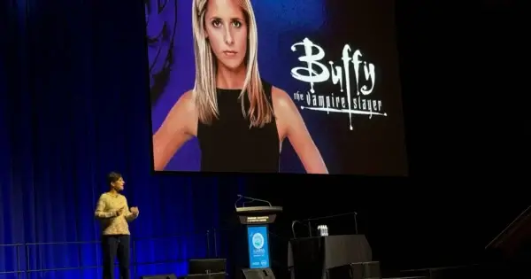 Speaker presenting with Buffy the Vampire Slayer backdrop.