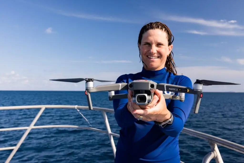 Karen holding drone on boat over ocean.
