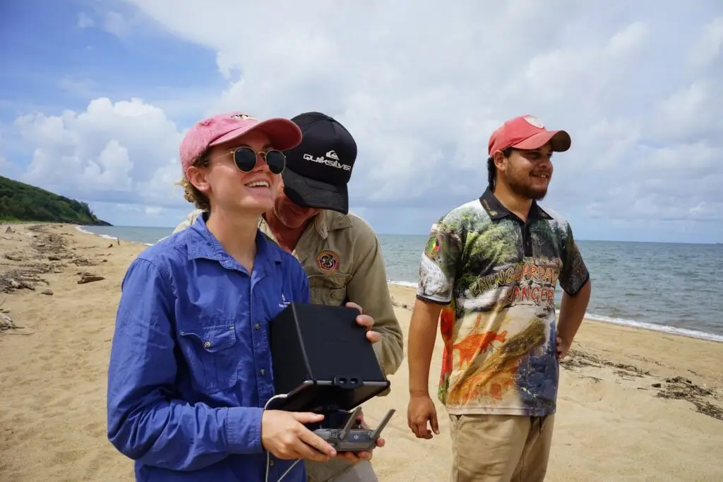 People operating drone on beach, sunny day