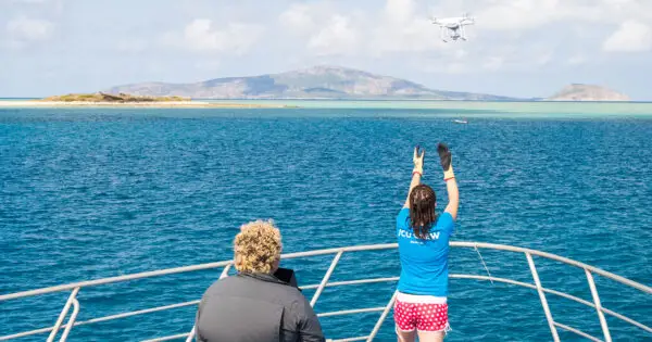 Person operating drone on a boat near islands.