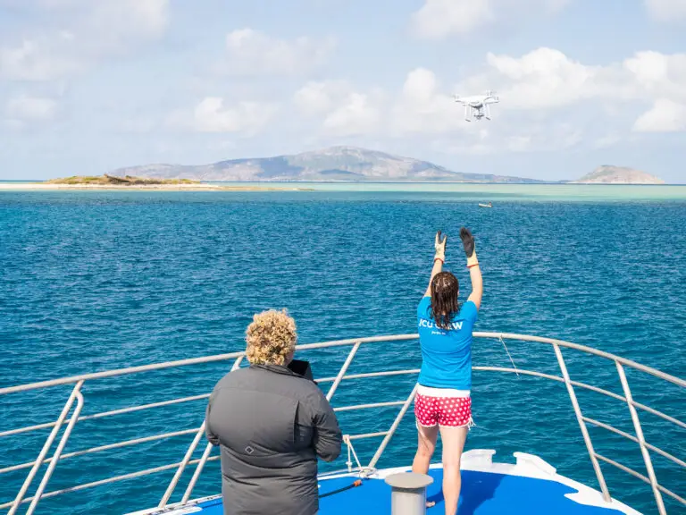 Person operating drone on a boat near islands.