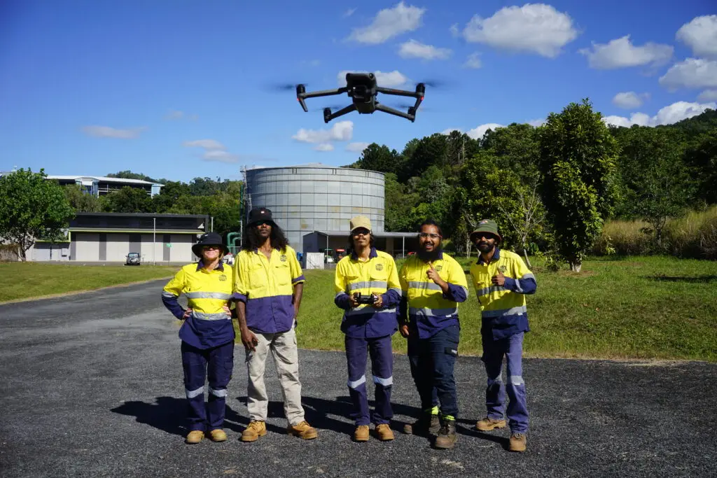 Five workers with a drone in rural setting.